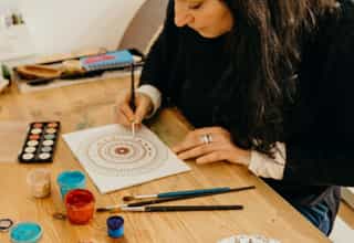 Young Woman painting on piece of paper on a table