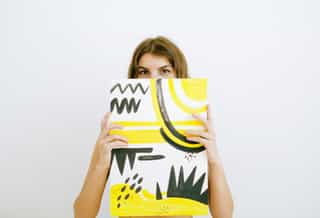 Woman holding a canvas in front of her face
