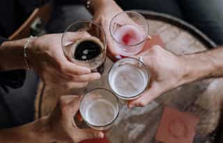 Group of adults drinking at a pub, putting their drinks together to say 'Cheers!'